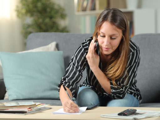 Young women on mobile phone while writing down notes on paper