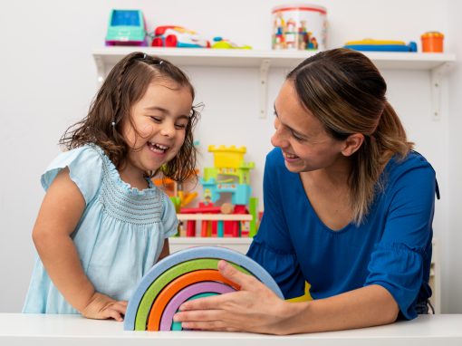 Kindergarten teacher and child playing with rainbow blocks