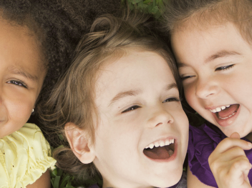 3 young girls laying in grass