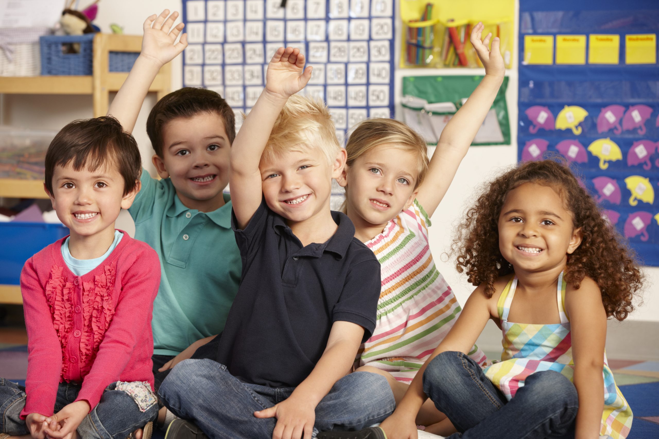 Group of kindergarten children, 3 with their hands raised