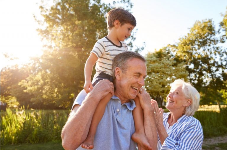 Child sitting on top of grandfathers shoulders with grandma standing next to them