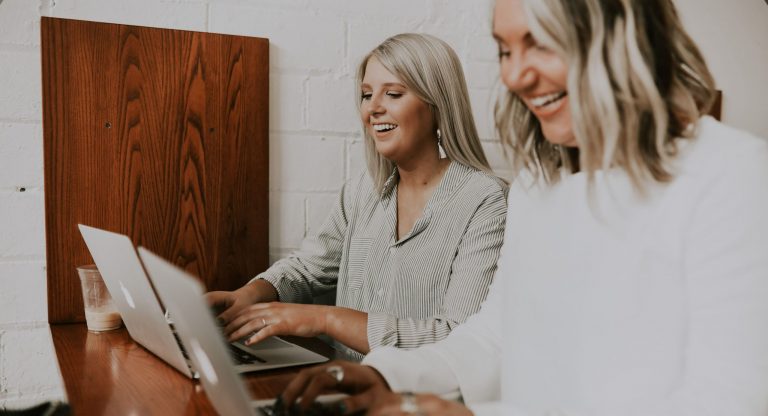 Two blond women on laptops