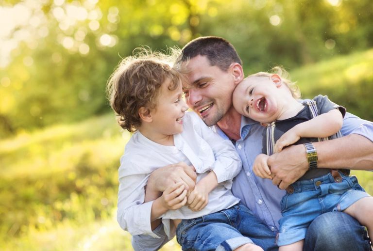 Happy dad hugging two happy children